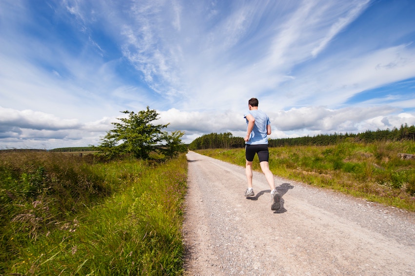 Staying active, staying healthy, staying motivated Photo from behind of a man running down a long dirt road