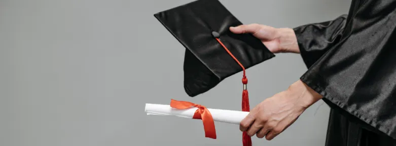 Photograph of student holding graduation cap and diploma.