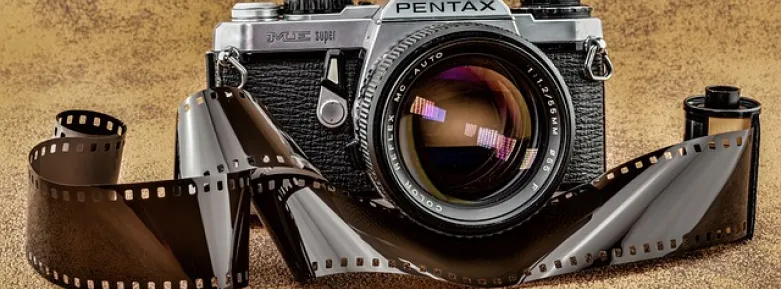 Analogue camera with strip of film in front of it.