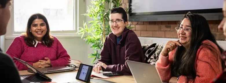 a group of people sitting at a table using a laptop computer
