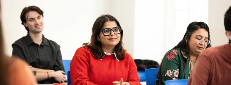 a group of people sitting at a table using a laptop
