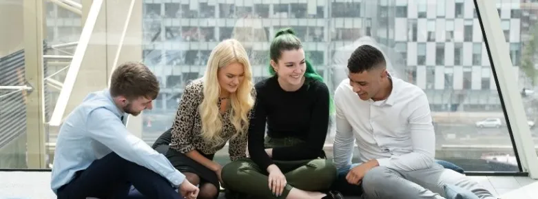 Four students sitting together on the floor working on a project