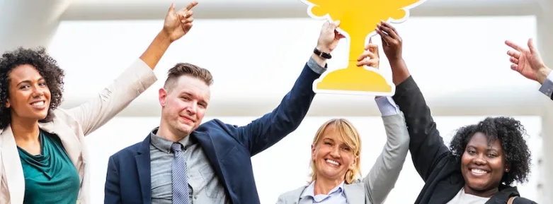 A thrilled team points to an oversize cut-out of a trophy