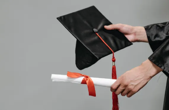 Photograph of student holding graduation cap and diploma.