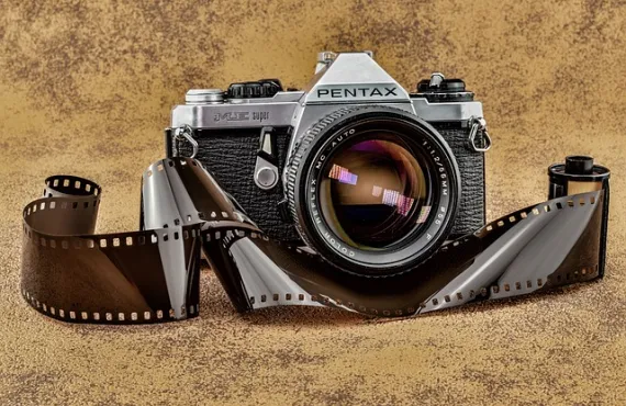 Analogue camera with strip of film in front of it.