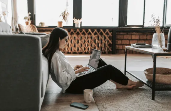 Smiling girl working from living room with a cup of tea