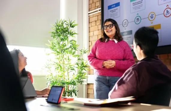 a group of people sitting at a table using a laptop