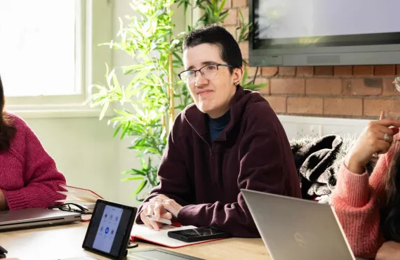 a group of people sitting at a table using a laptop computer