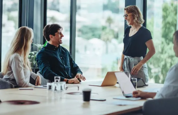 a group of people sitting at a table looking at a laptop