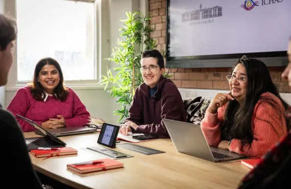 a group of people sitting at a table using a laptop computer