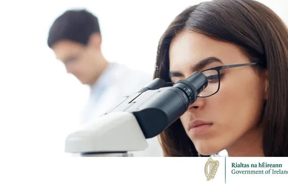 a woman talking in a lab with a microscope