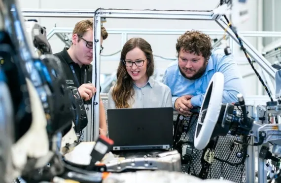 Three apprentices around a computer