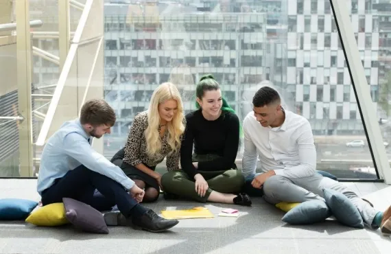 Four students sitting together on the floor working on a project