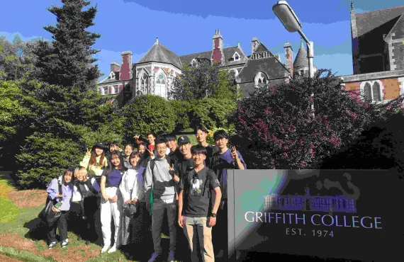 A group of Japanese students standing next to Griffith College Cork sign