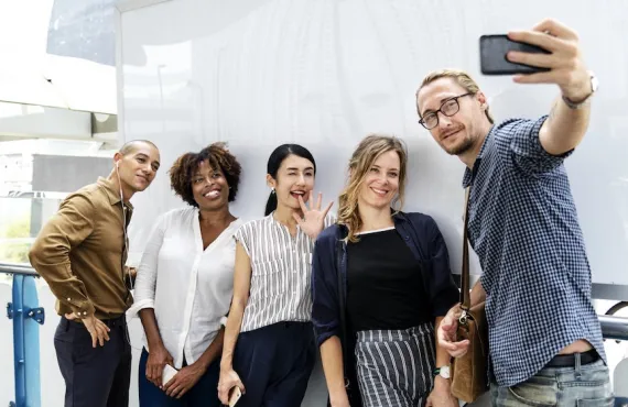 A smiling group recording a video on a phone