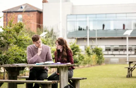Students sitting at a picnic table on the grass at Griffith College Dublin