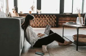 Smiling girl working from living room with a cup of tea