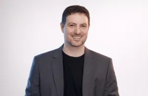 a man wearing a suit and tie smiling at the camera