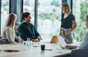 a group of people sitting at a table looking at a laptop