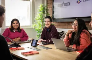 a group of people sitting at a table using a laptop computer