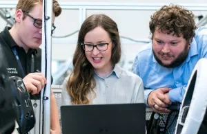 Three apprentices around a computer