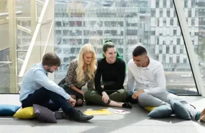 Four students sitting together on the floor working on a project