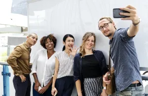 A smiling group recording a video on a phone
