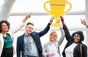 A thrilled team points to an oversize cut-out of a trophy