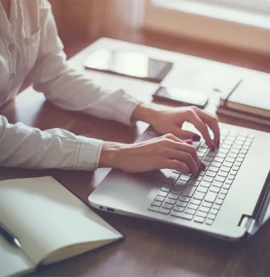 a person sitting at a desk using a laptop computer