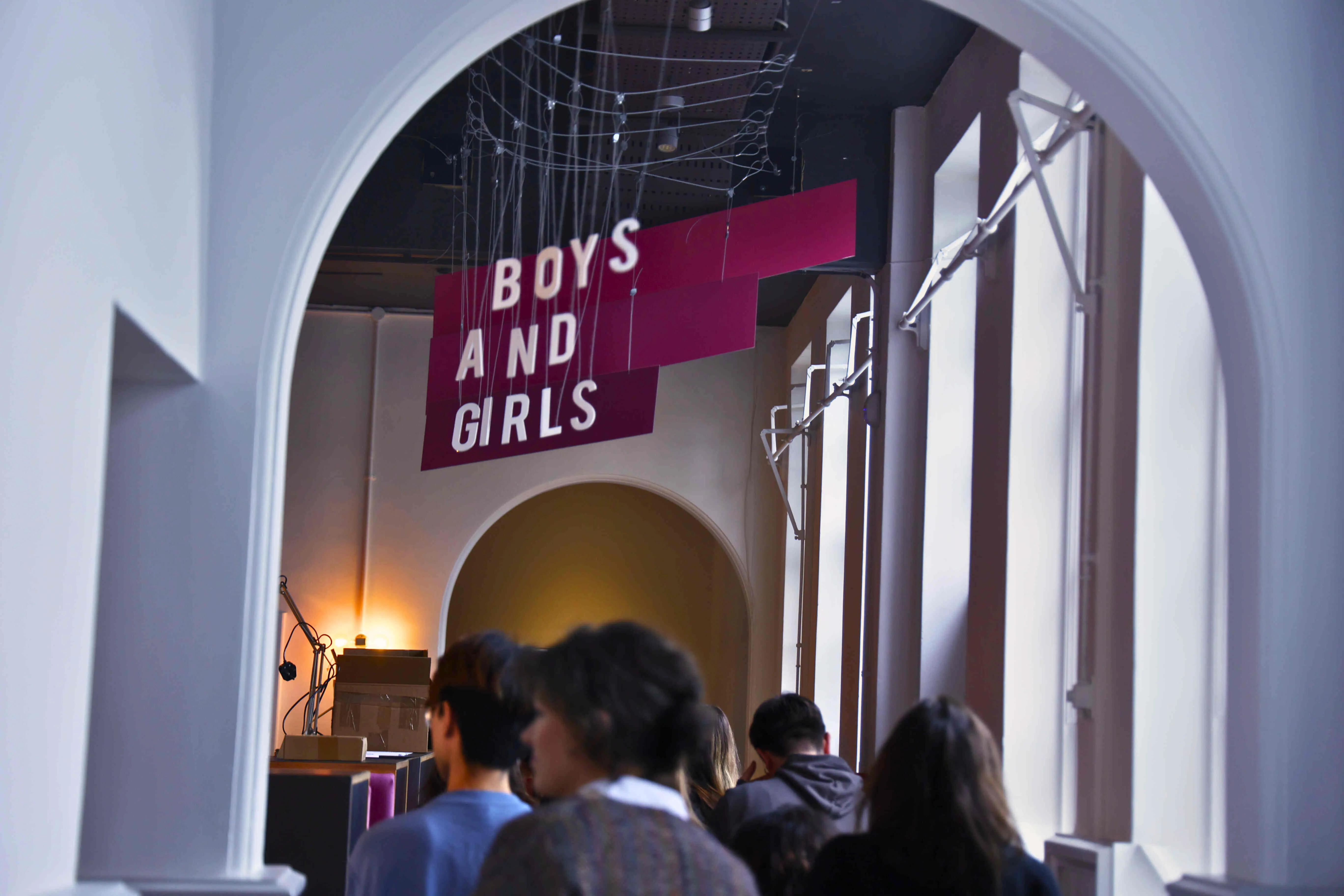 a group of people standing in front of a sign saying Boys+Girls
