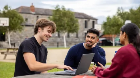 a group of people sitting at a table using a laptop