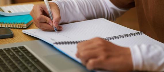 a person using a laptop computer sitting on top of a wooden cutting board