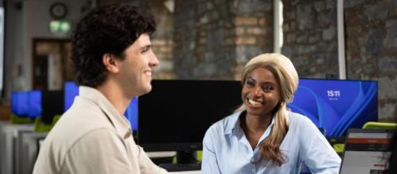 two people smiling at a desk