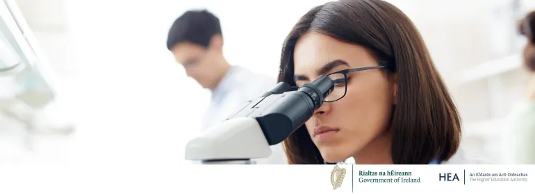 a woman talking in a lab with a microscope