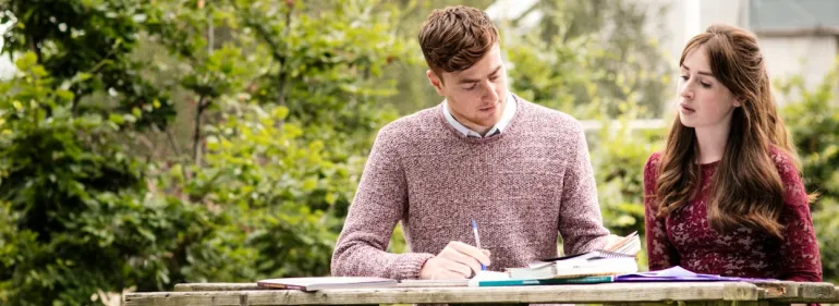 a man and a woman standing in front of a laptop