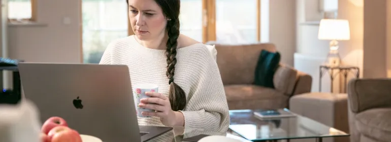 A woman working remotely from her kitchen table.