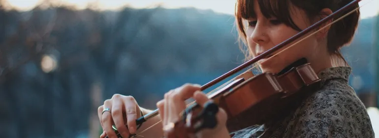A woman playing fiddle outside