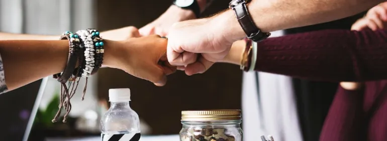 Multiple students fist-bumping above a table