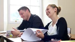 Mature female and male student laughing in class