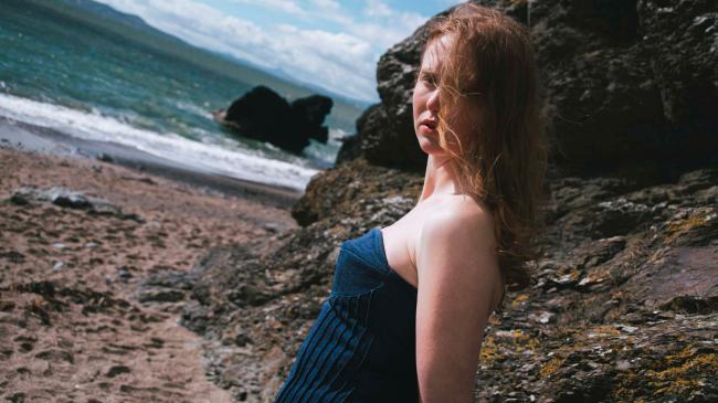 a woman standing on a rocky beach