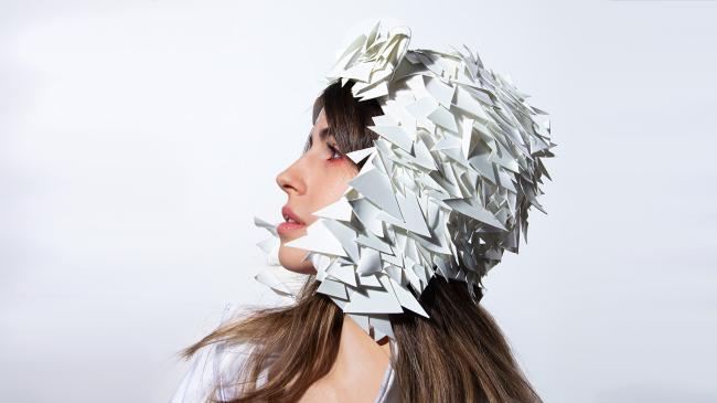 A side profile, close-up of a model wearing a white sequined hat  