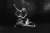 Black and white image of dramatic staged pose with two performers intertwined on a dark background.