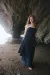 Model wearing denim corset and denim asymmetric skirt over a chiffon underskirt with rough coastal rock in background.