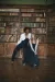 Two models wearing denim trousers, corset and báinín jacket, and denim corset and denim asymmetric skirt over a chiffon underskirt, posed in a library.