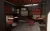 Interior render of a dimly lit vinyl listening bar with booth seating, round terrazzo tables, and a vinyl station under red acoustic ceiling panels.