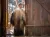 A child wearing a long, shaggy, two‑tone fur costume stands in a doorway with sunlight behind them.