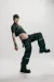Male model, in an active pose, wearing a black denim top and black denim jeans.