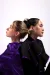 A model wearing a purple silk satin blouse and a second model wearing a black blouse with purple trim