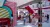 Open-plan entrance area with bright red staircase, seating booths, and colourful  geometric wall features creating a vibrant social hub.