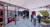 Flexible office and circulation space with open desks, glass partitions, and creative wall  murals, finished with concrete flooring and rubber wayfinding lines.